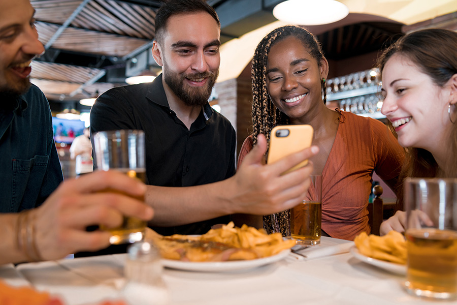 Group of friends looking at referral on phone at restaurant 