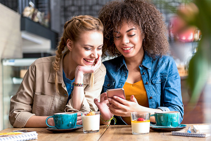 Group of friends looking at referral on phone at restaurant 