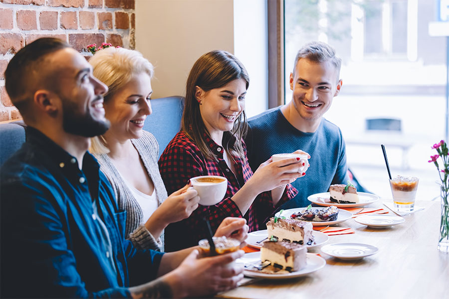 Group of friends interacting with waiter at restaurant