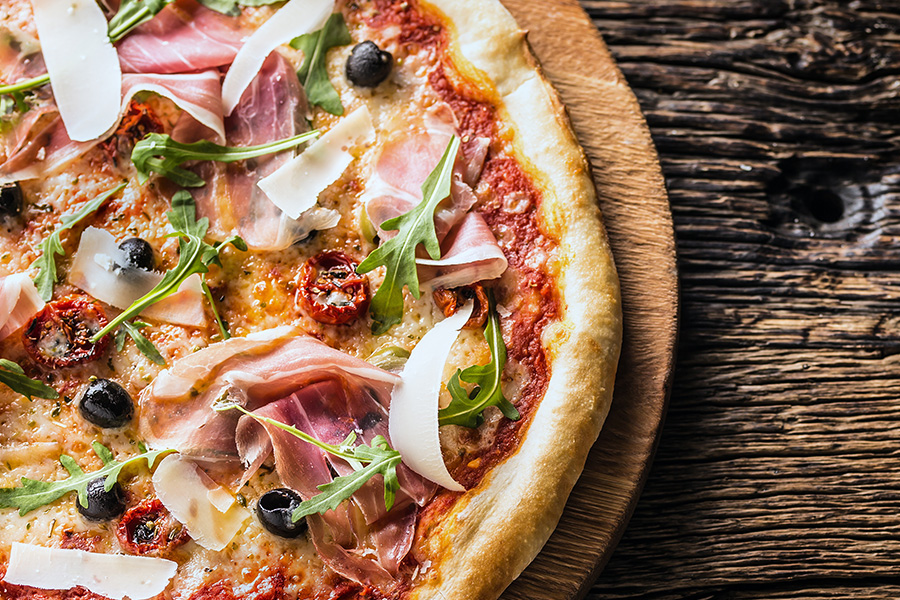 hot honey prosciutto pizza on a wooden board